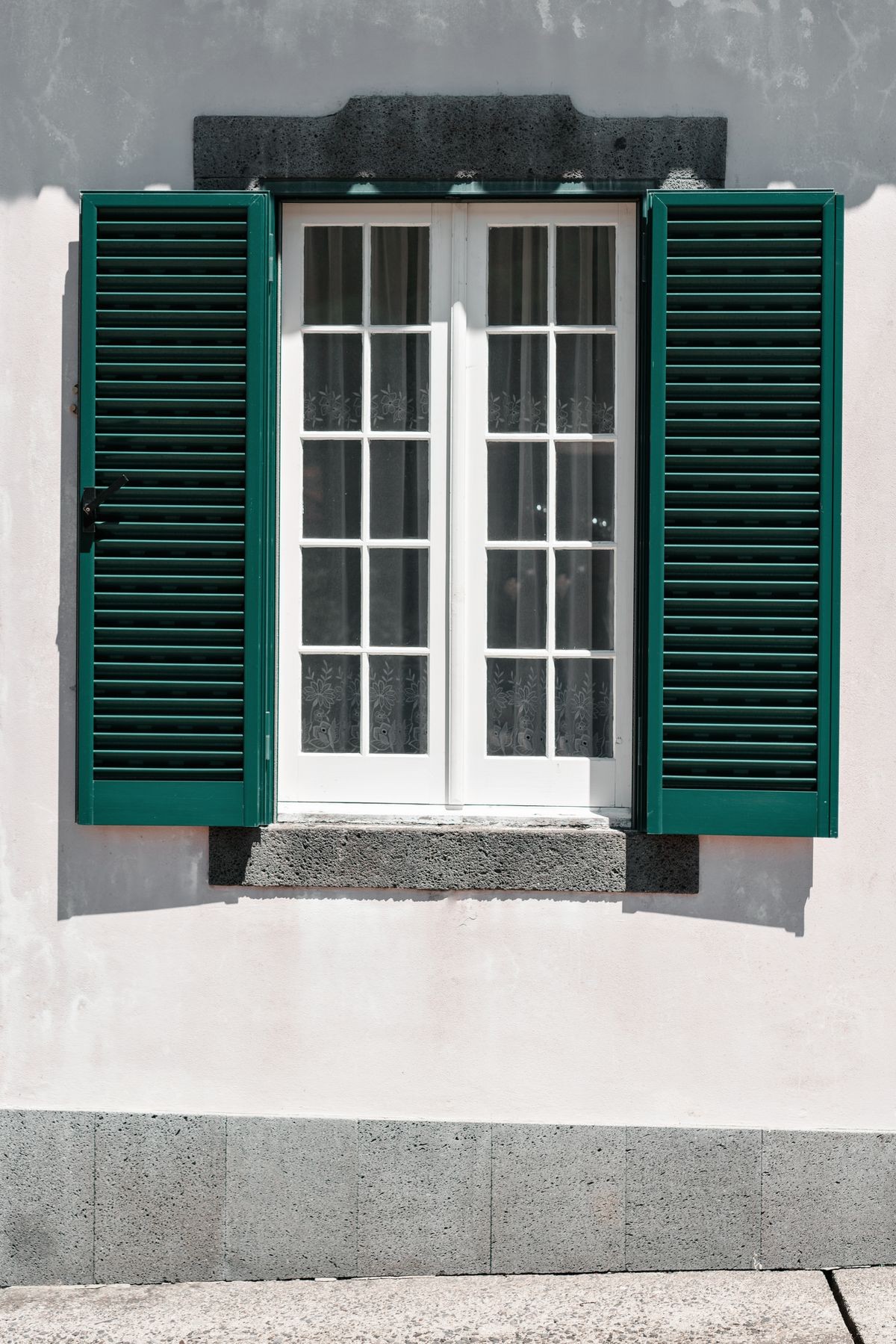 Ornamental facade of colorful house in Sao Miguel, Azores. Portugal. Beautiful old tiny houses, green doors and window shutters